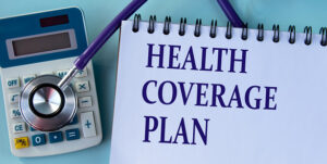 HEALTH COVERAGE PLAN - words on a white sheet against the background of a stethoscope and a calculator.