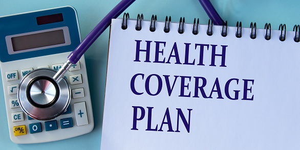 HEALTH COVERAGE PLAN - words on a white sheet against the background of a stethoscope and a calculator.